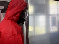 Remove  Asbestos operative entering an enclosure wearing red overalls and RPE